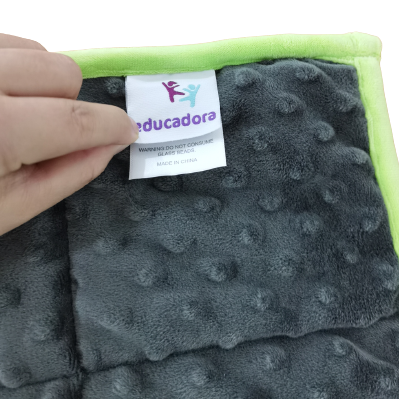 Gewichtetes Lap Pad - Educadora hilft Kindern mit besonderen Bedürfnissen, sich zu beruhigen.